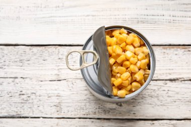 Hafif ahşap arka planda mısır taneleri olan teneke kutu.