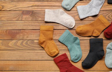 Ahşap arka planda farklı bebek çorapları, yakın plan.