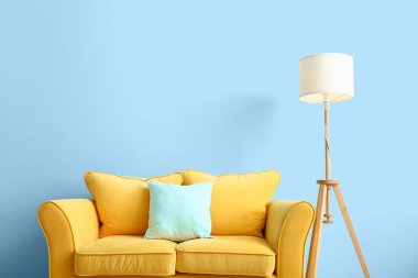 Rahat bir kanepe ve renkli duvarın yanında modern bir lamba.