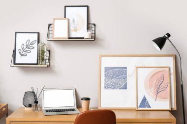 Bilgisayarlı modern işyeri ve ışık duvarının yanındaki resimler.