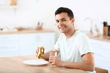 Mutfakta lezzetli sandviçleri olan genç adam.