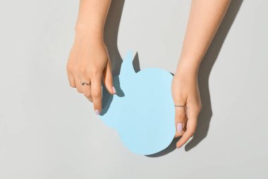 Güzel manikürlü ve şık takılı bir kadın gri arka planda kağıt konuşma balonu tutuyor.