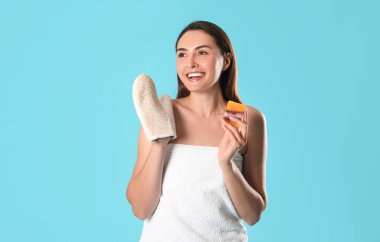 Arka planda sabun ve banyo eldiveni olan güzel genç bir kadın.