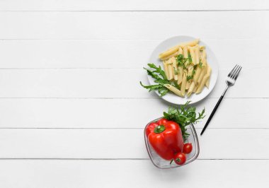 Hafif ahşap zemin üzerinde lezzetli makarna ve sebze tabağı