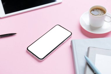 Renkli arka planda cep telefonu ve bir fincan kahve, yakın plan.