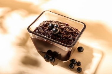 Arka planda siyah frenk üzümü reçeli olan kase