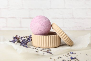 Hafif tuğla duvarın yanındaki masada lavanta banyosu bombası.