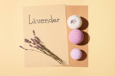 Banyo bombaları, çiçekler ve renkli arka planda LAVENDER sözcüğü olan kağıtlar.