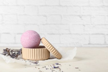 Hafif tuğla duvarın yanındaki masada lavanta banyosu bombası.