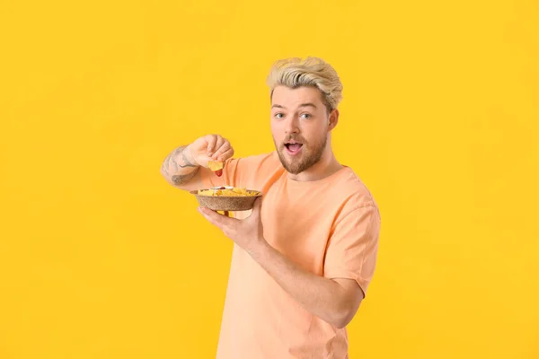 Handsome Young Man Eating Tasty Nachos Color Background — Stock Photo, Image