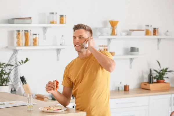 Handsome Young Man Talking Phone While Eating Tasty Quesadilla Home — Stock Photo, Image