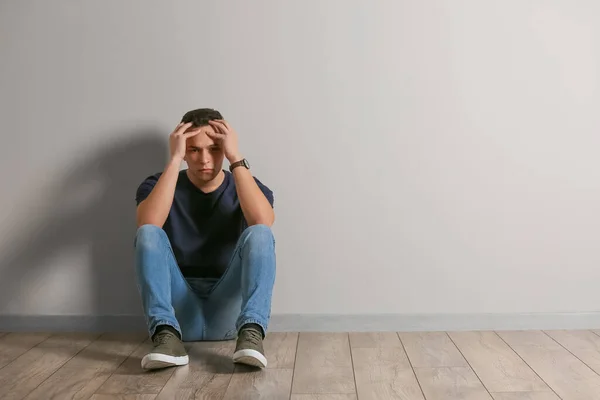 Депресивний Молодий Чоловік Сидить Біля Світлої Стіни — стокове фото