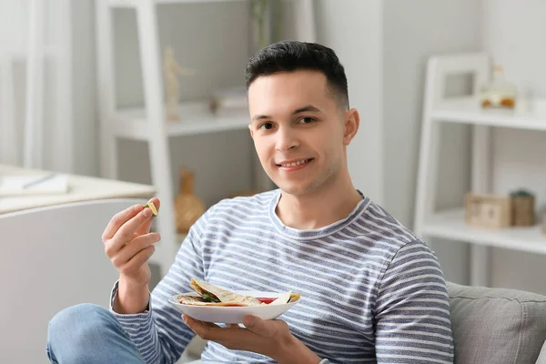 Evde lezzetli quesadilla yiyen yakışıklı genç adam.