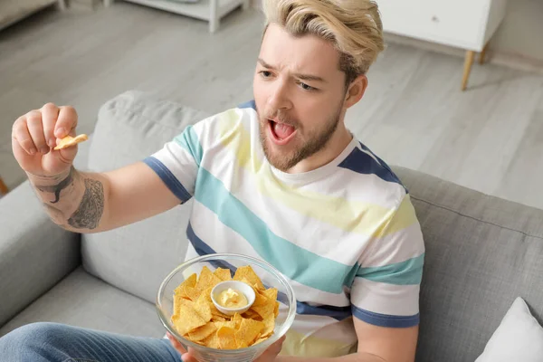 Schöner Junger Mann Isst Leckere Nachos Während Hause Fernsieht — Stockfoto