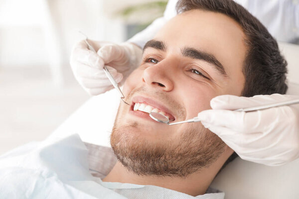 Dentist examining teeth of young man in clinic
