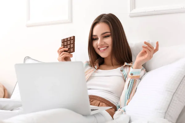 Wanita Muda Dengan Laptop Makan Coklat Lezat Kamar Tidur — Stok Foto