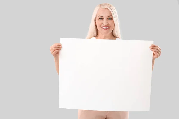 带有浅色背景空白海报的成熟女人 — 图库照片