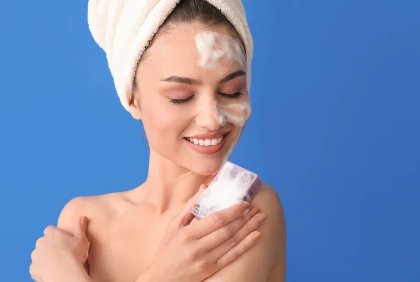 Beautiful young woman with soap on color background