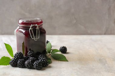 Lezzetli böğürtlen reçeli ve gri arkaplanda böğürtlen kavanozu