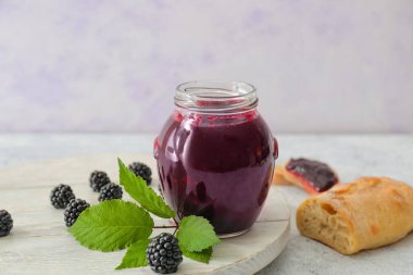 Lezzetli böğürtlen reçeli kavanozu ve hafif arkaplanlı ekmek kompozisyonu