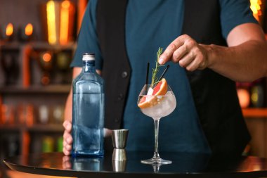 Erkek barmen bardaki masada greyfurt cini ve tonik yapıyor.