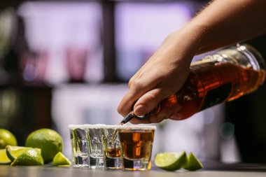 Barmen bardaki masada bardaklara lezzetli tekila dolduruyor.