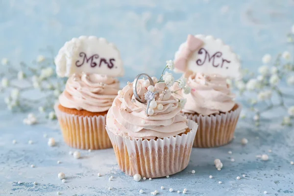 Tasty cupcakes and wedding rings on table