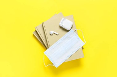 Renkli kitaplara ve tıbbi maskeye sahip modern kulaklıklar