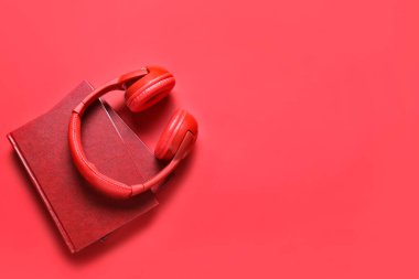 Renk arkaplanı üzerine kitapları olan modern kulaklıklar