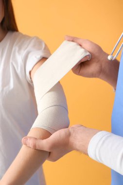 Doktor, genç bir kadının koluna renk desteği uyguluyor.