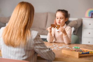 Otistik bozukluğu olan küçük bir kız çocuk psikologunun ofisinde bulmaca çözüyor.