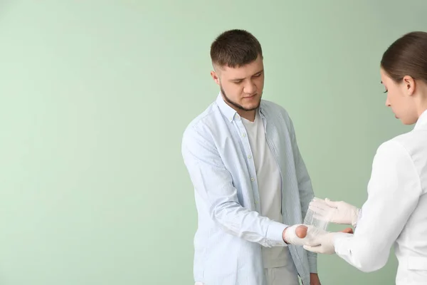 医師適用包帯に手の若い男の色の背景 — ストック写真