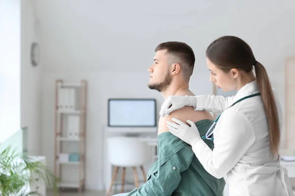 Läkare Applicera Plåster Axeln Ung Man Kliniken — Stockfoto