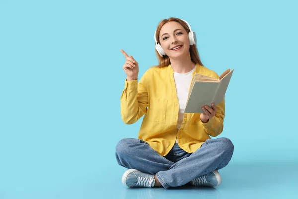 Ältere Frau Mit Buch Zeigt Auf Etwas Auf Farbigem Hintergrund — Stockfoto