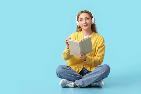 Ältere Frau Mit Kopfhörern Liest Buch Auf Farbigem Hintergrund — Stockfoto