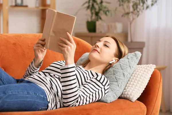 Mature Woman Earphones Reading Book Home — Stock Photo, Image