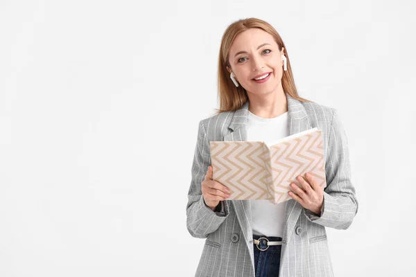 Ältere Frau Mit Kopfhörern Liest Buch Auf Weißem Hintergrund — Stockfoto