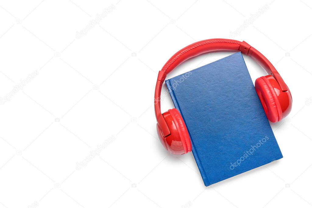 Modern headphones with book on white background