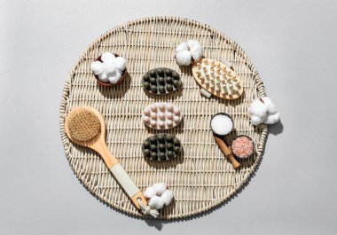 Masaj sabunları, banyo malzemeleri ve gri arka planda pamuk çiçekleri olan kompozisyon