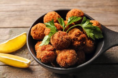 Lezzetli morina pirzolası ve ahşap arka planda limon ile kızartma tavası, yakın plan.