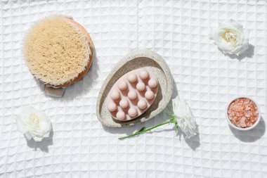 Masaj sabunu, deniz tuzu, fırça ve çiçeklerle dolu bir kase.