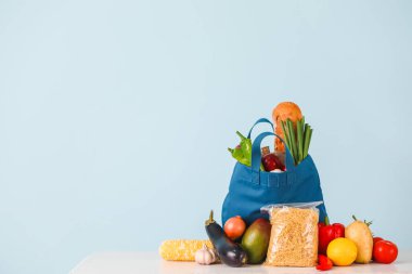 Renkli duvarın yanındaki masada yiyecek olan alışveriş torbası.