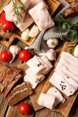 Ahşap zemin üzerinde tuzlanmış domuz yağı, ekmek ve taze sebzeler olan bir tahta.