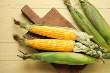Tahtada taze mısır koçanı ve renkli ahşap arka plan