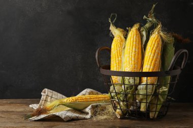 Tahta masada taze mısır koçanları olan sepet.