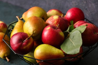 Olgun armutlu sepet ve koyu arka planda elmalar, yakın plan.