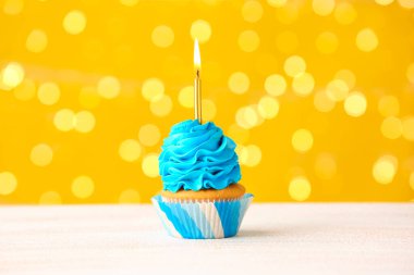 Bulanık ışıklara karşı yanan mumlu leziz bir doğum günü keki.