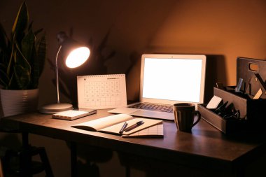 Renkli duvarın yanında parlayan lamba ve bilgisayarlı modern işyeri