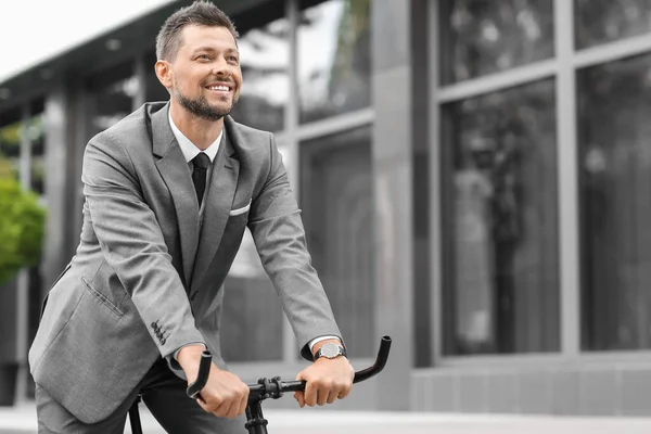 Businessman going to work by bicycle on city street