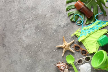 Çocuklar için plaj aksesuarları, mayo, bir şişe güneş kremi ve grunge arka planda palmiye yaprağı.